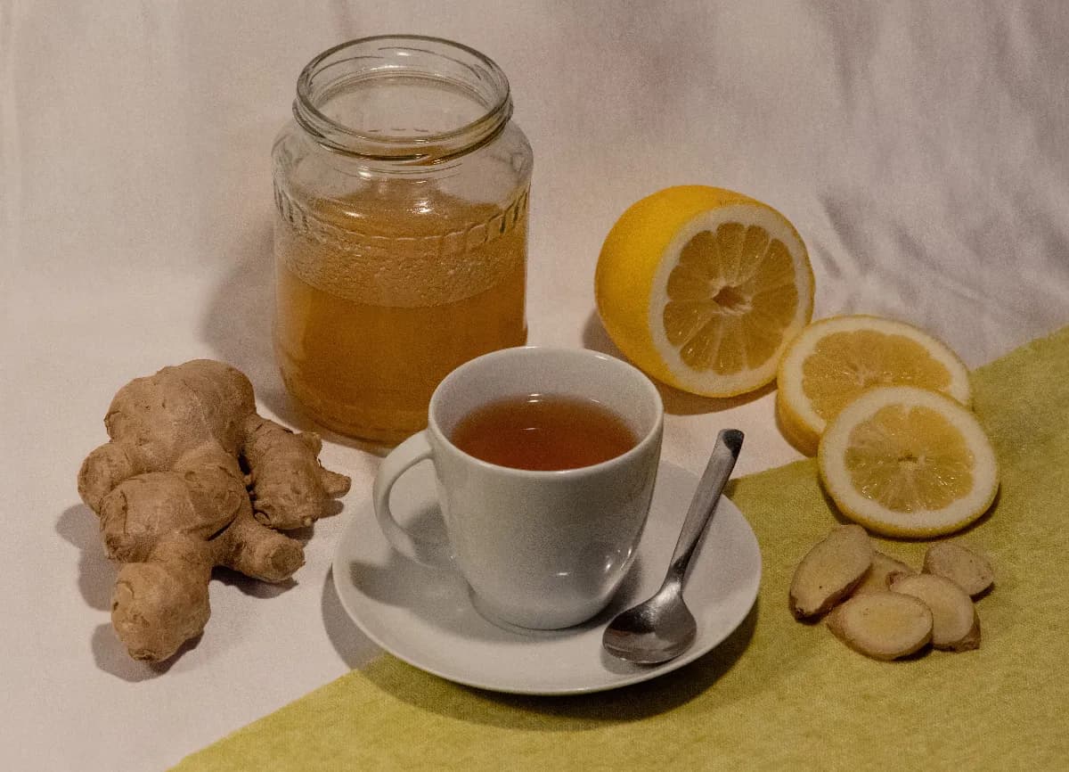 Taza de té de jengibre con rodajas frescas de jengibre sobre una mesa de madera
